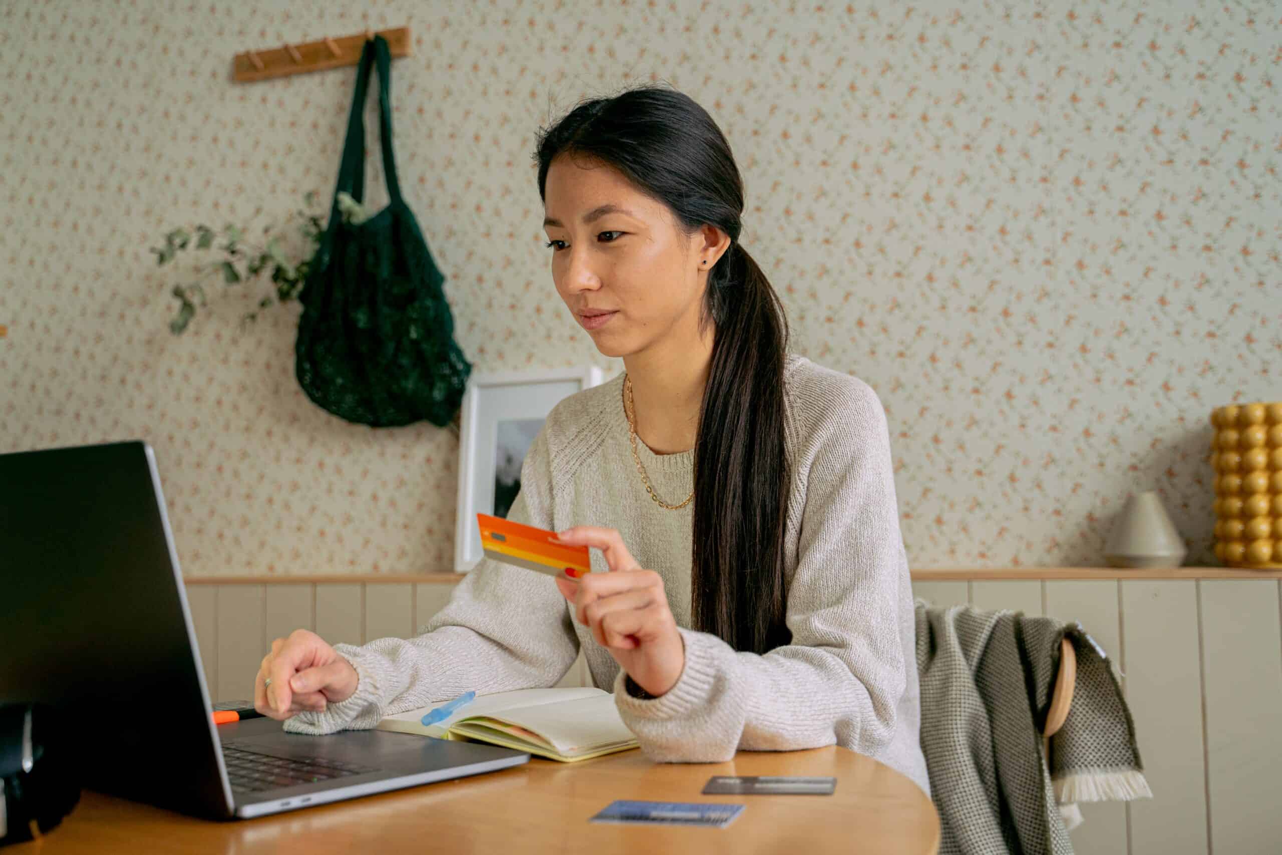 Woman holding credit card while looking at laptop.