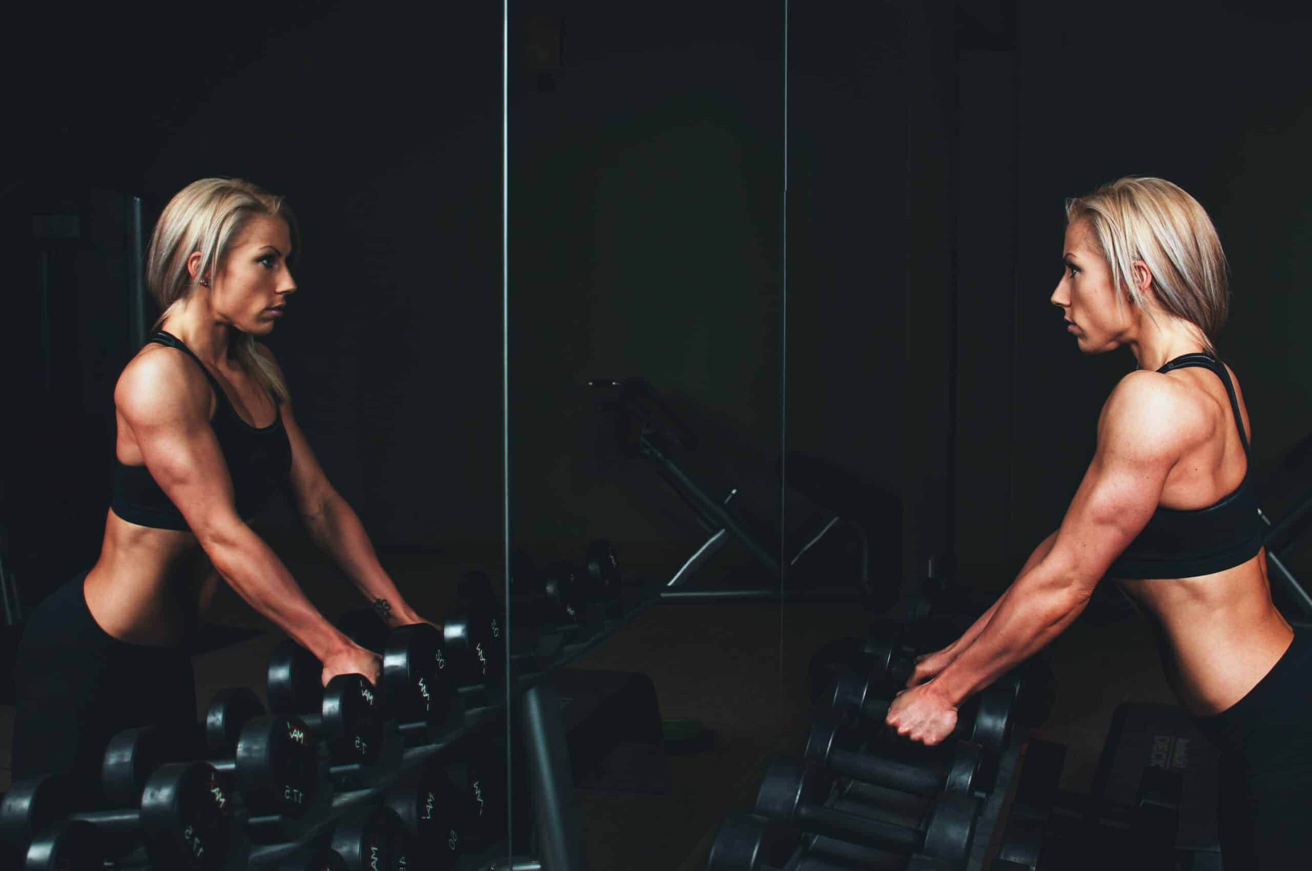 woman holding dumbbells looking in mirror.