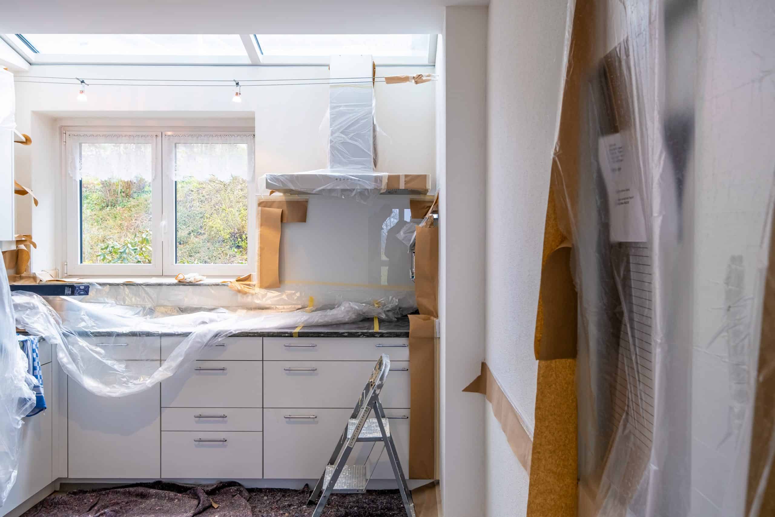 Kitchen counters and cabinets covered with plastic covers.