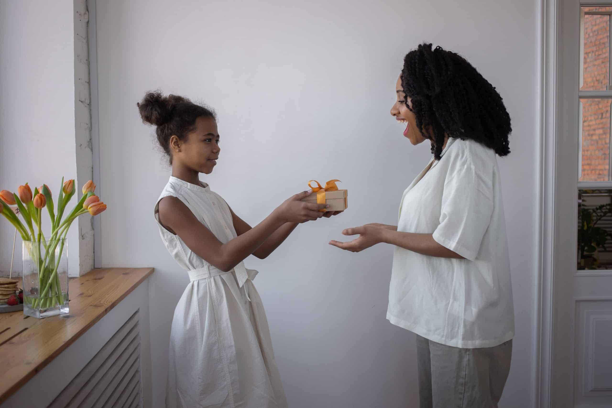 Daughter handing a small gift to her mother