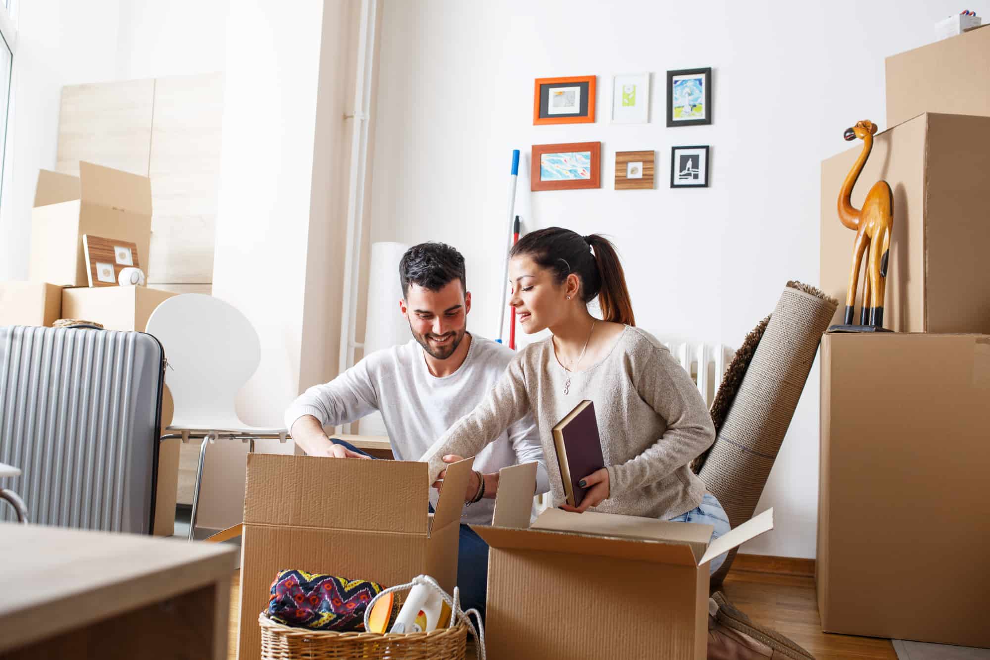 Young couple packing and unpacking cardboard boxes.