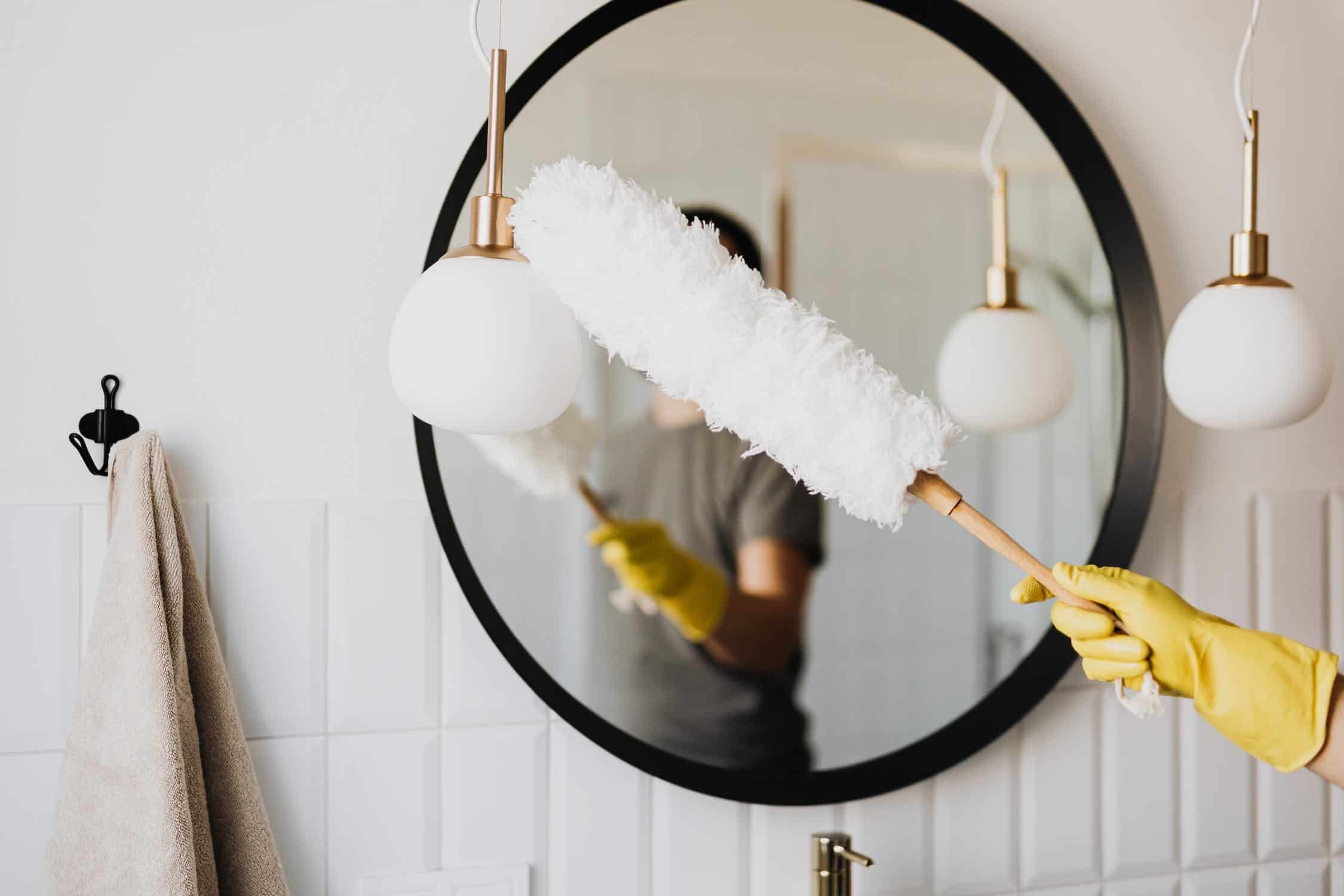 A person dusting the mirror.