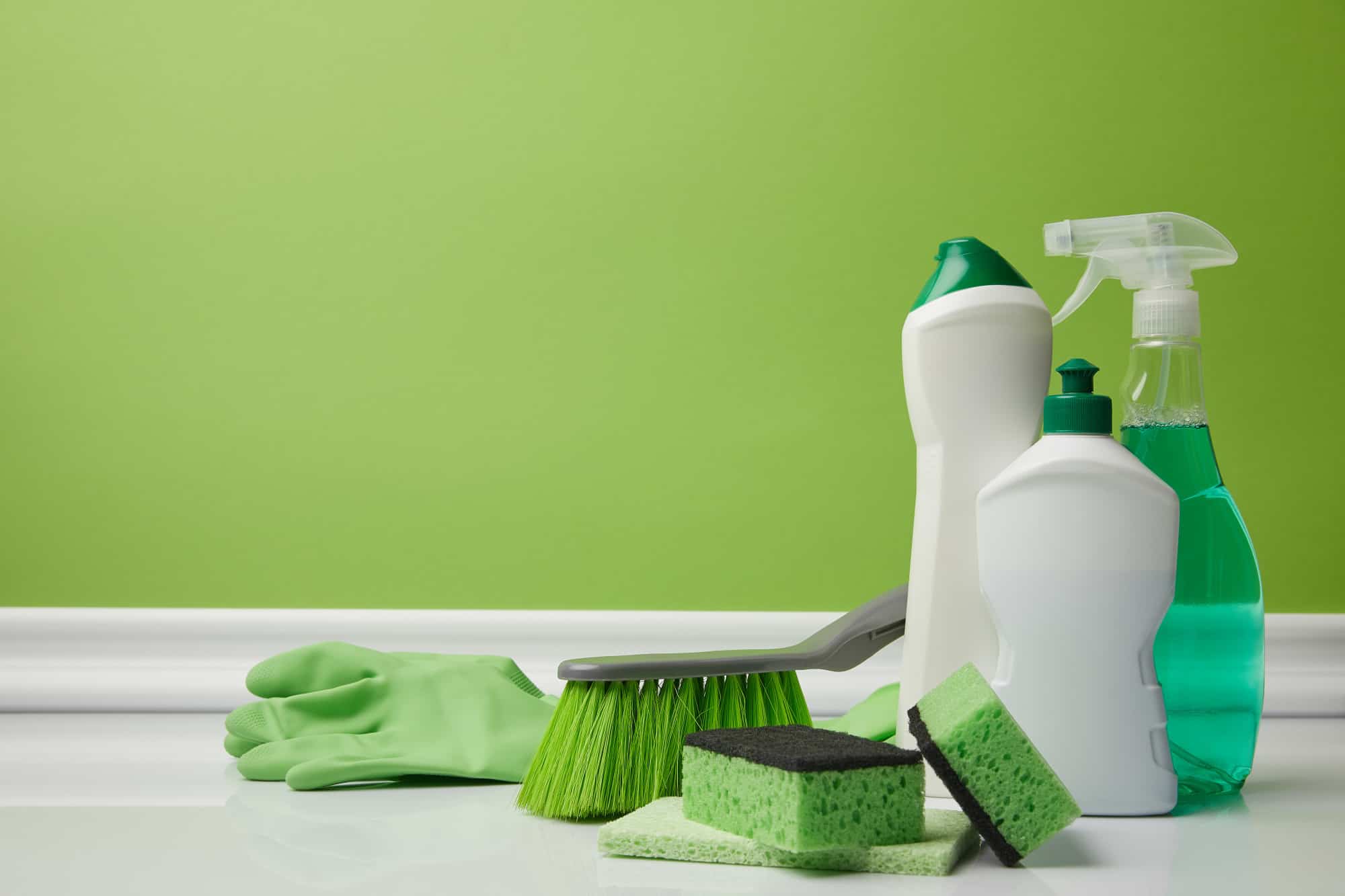 Cleaning bottles and supplies against a green background.