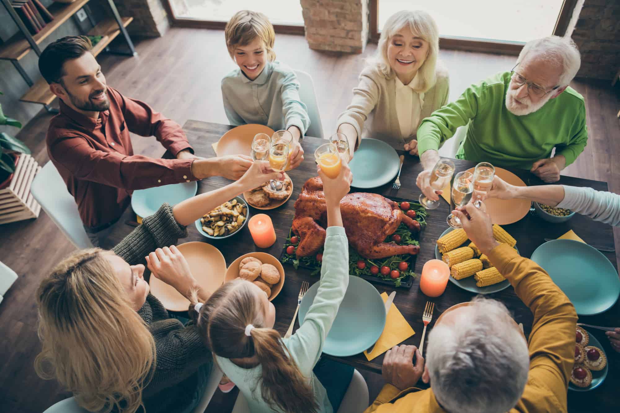 Cheerful big full family brother sister couples eating tasty yummy brunch feast tradition clinking glass in loft brick industrial style interior house indoors