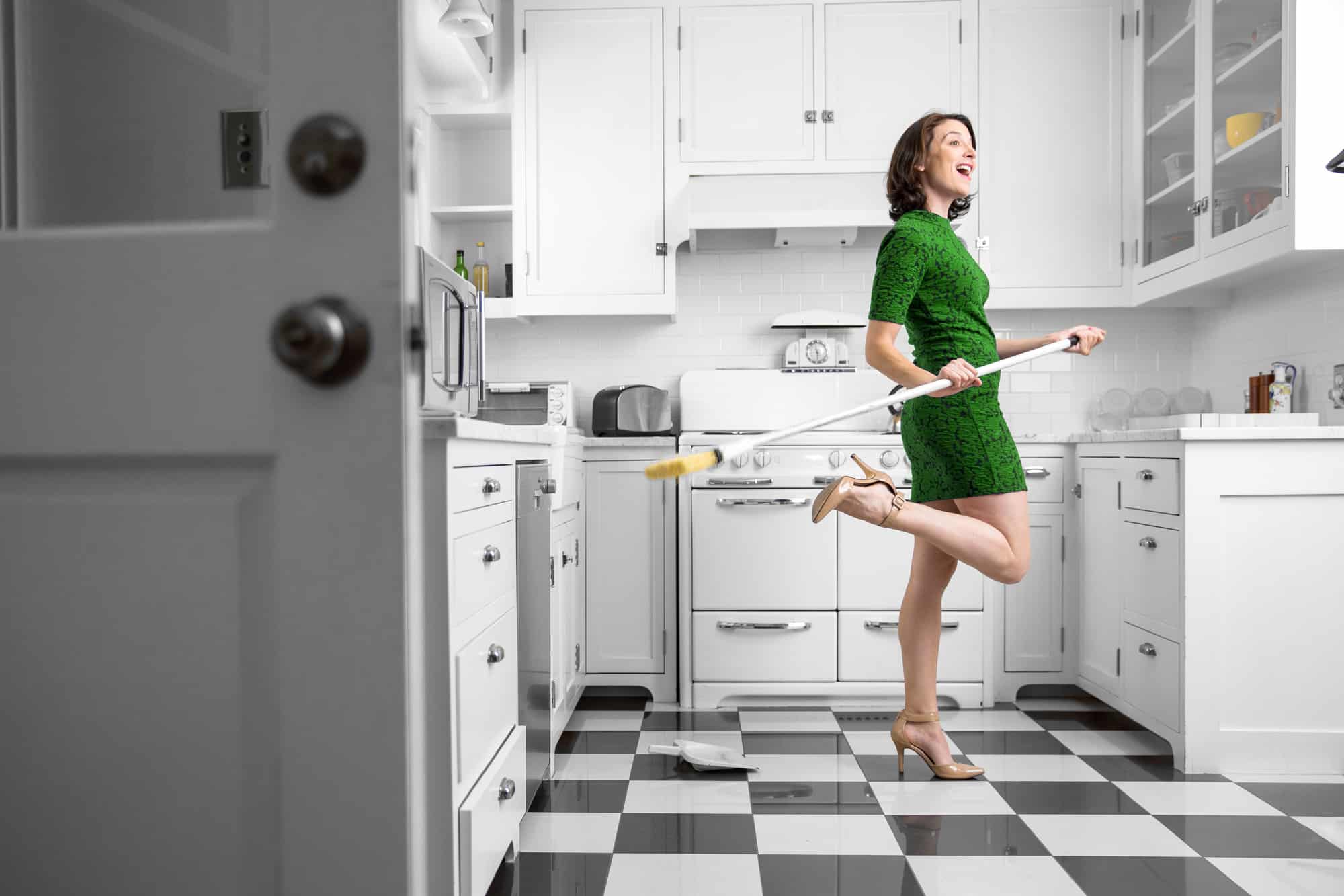 Happy and dancing housewife holding a broom.