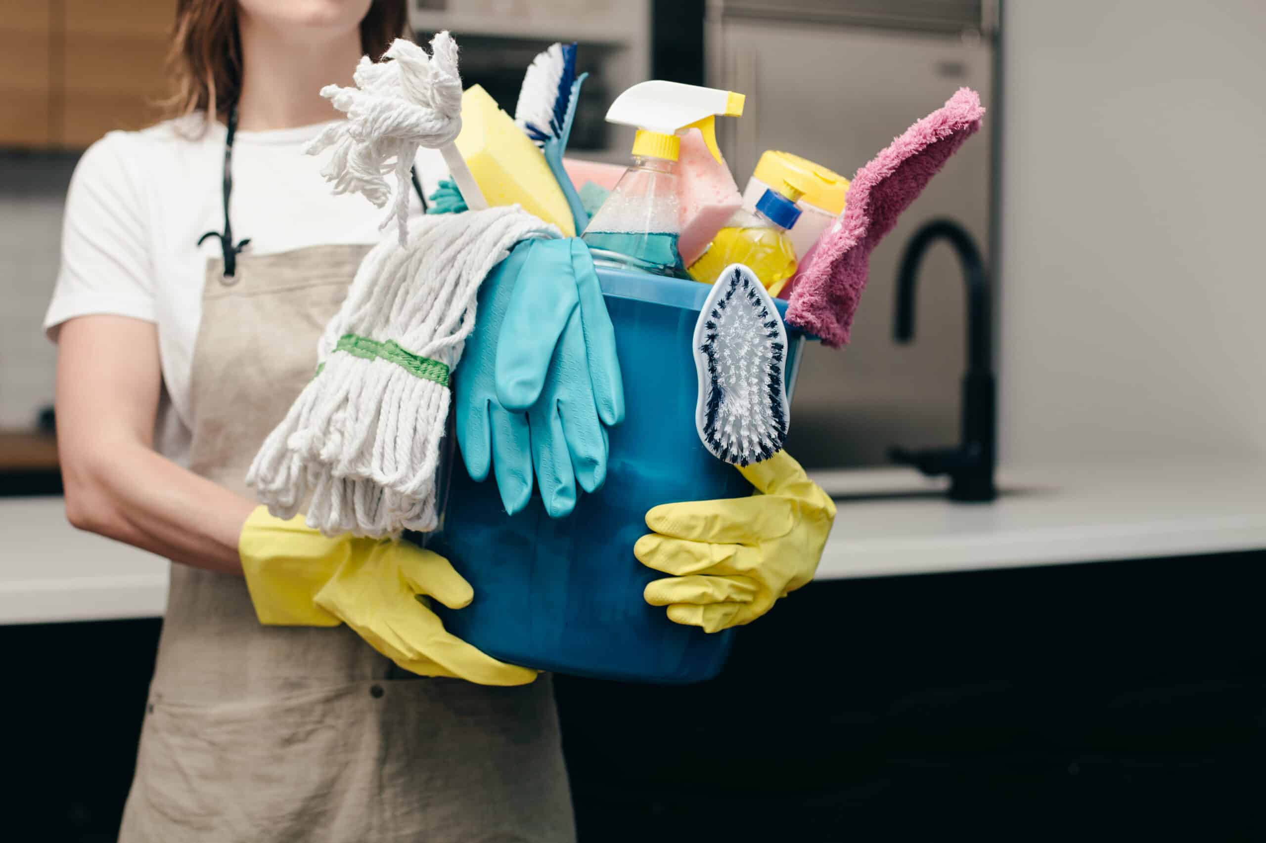 Woman holding bucket of cleaning supplies.