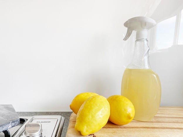 Lemons and a spray bottle on a kitchen counter.