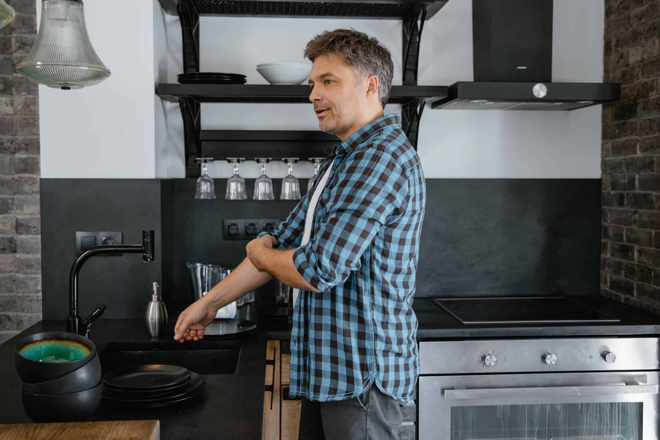 Man rolling up sleeves and preparing to wash dishes.