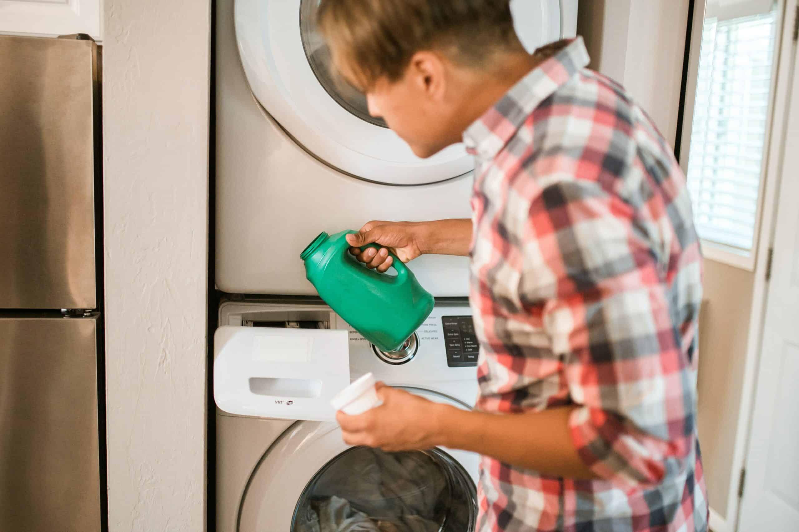 Man filling washing machine with septic-safe laundry detergent.