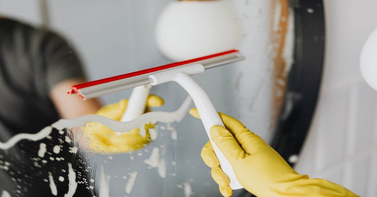 Person drying mirror with squeegee.