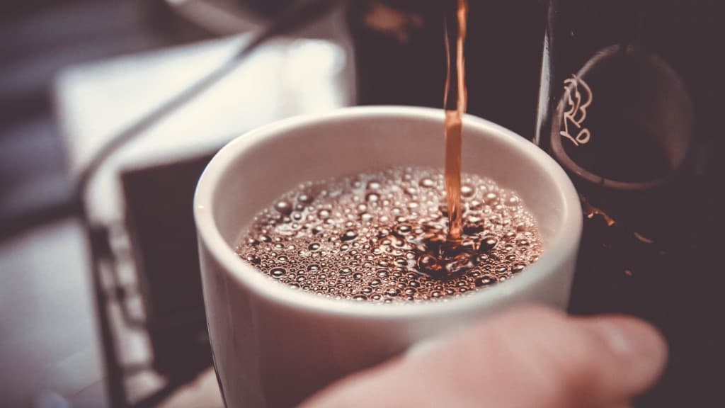 Coffee maker filling coffee mug.