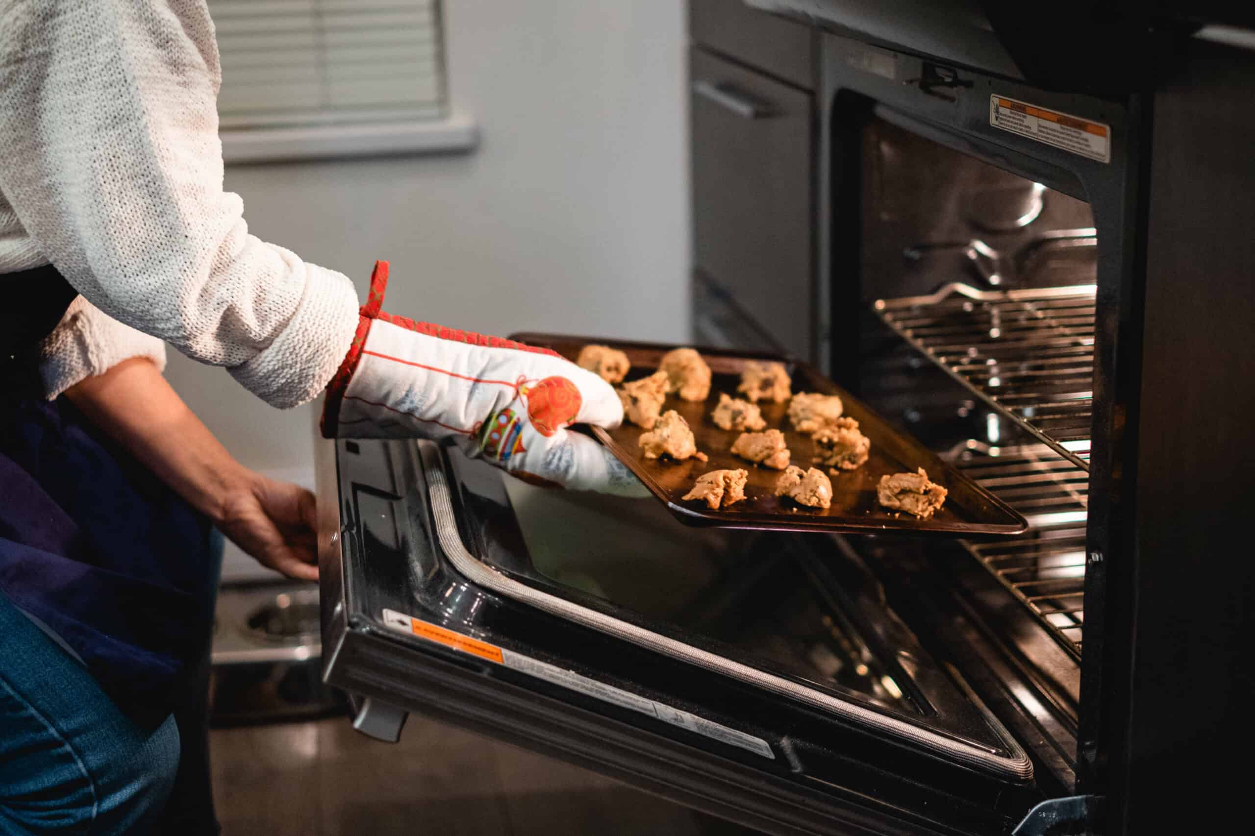 Person putting a sheet of cookies in the oven.