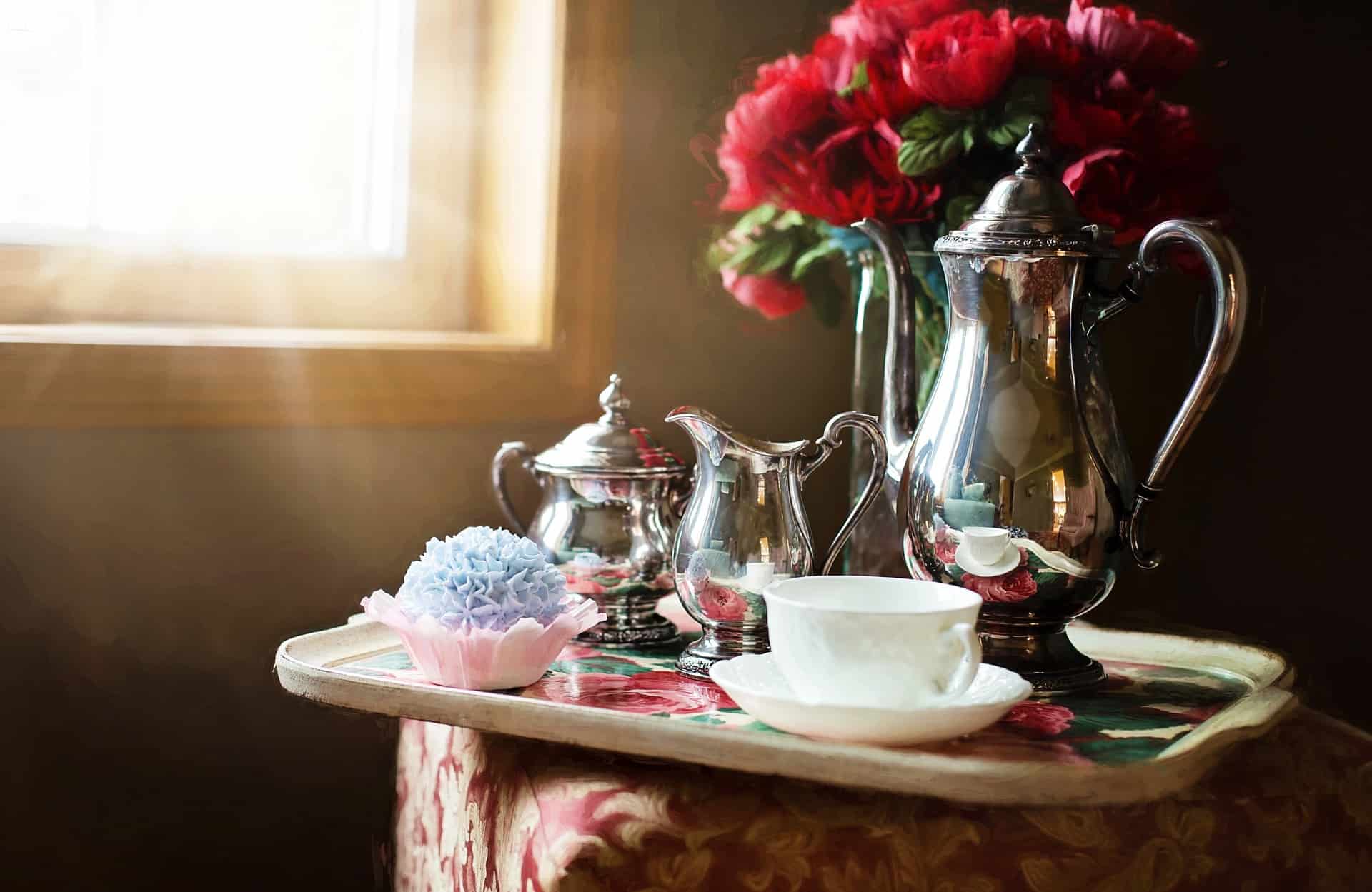 Silver tea set with vase of roses.