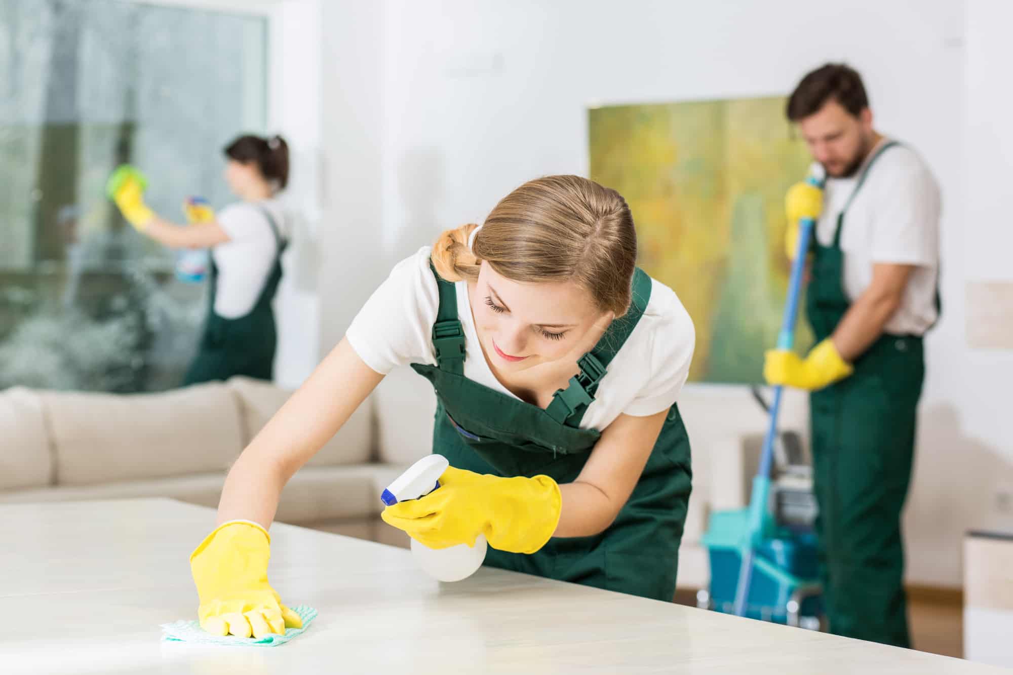 Young girl working as a professional cleaner and wiping down a table.