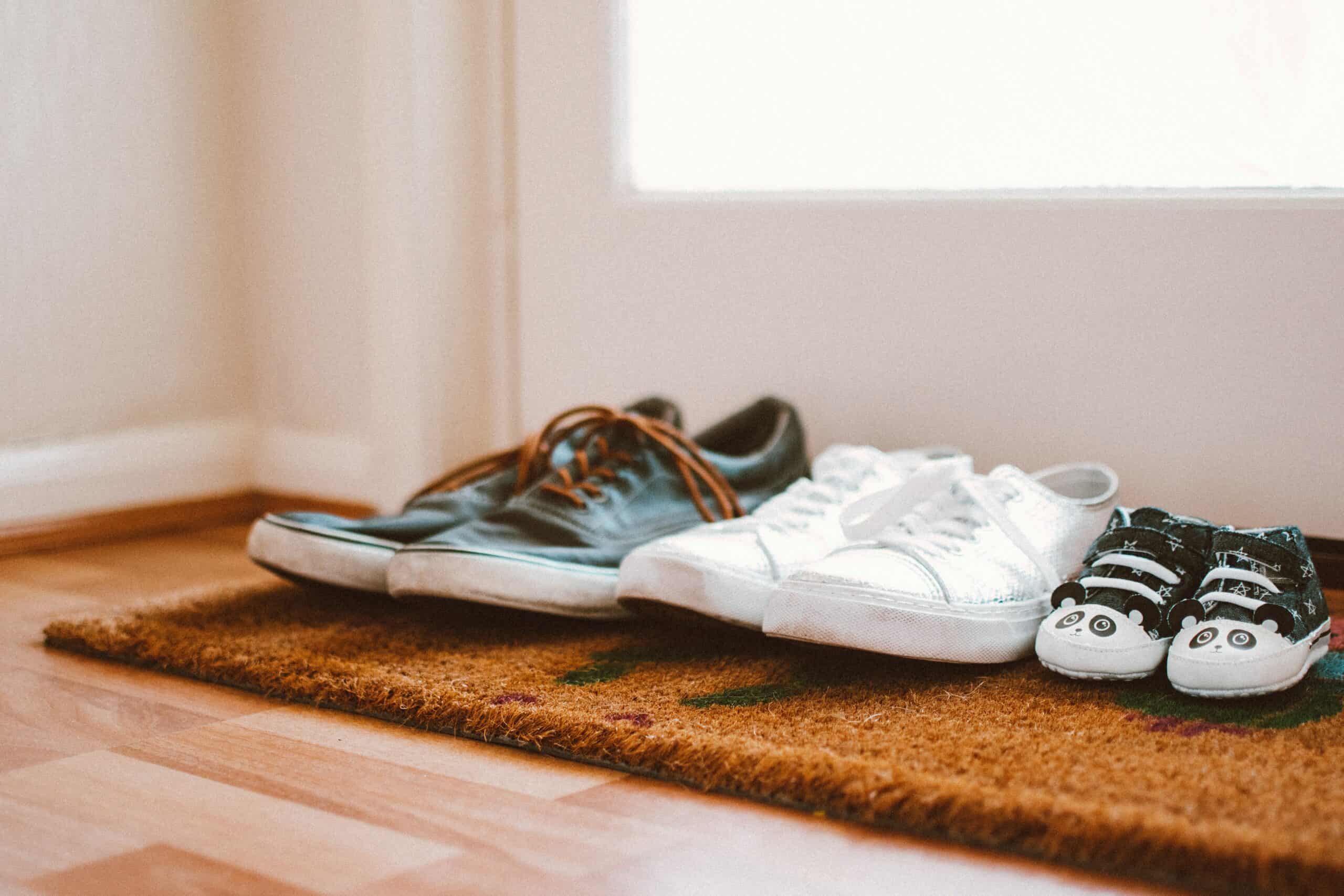 Three pairs of shoes on entry mat.