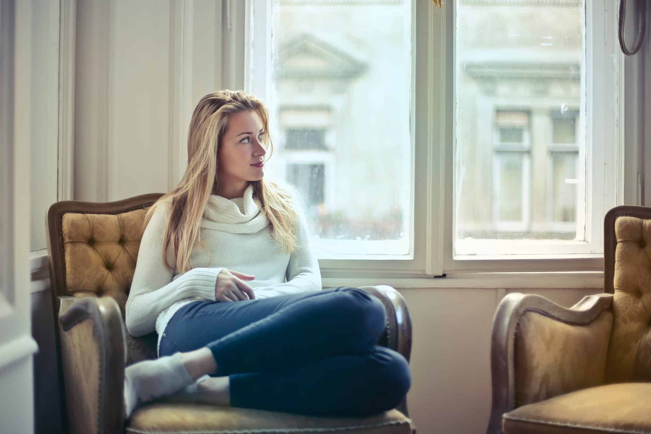 Woman sitting relaxed in an armchair by the window.