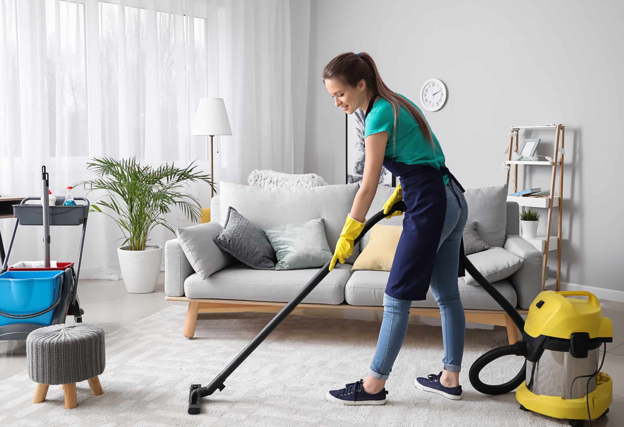 Young woman vacuuming in the living room.