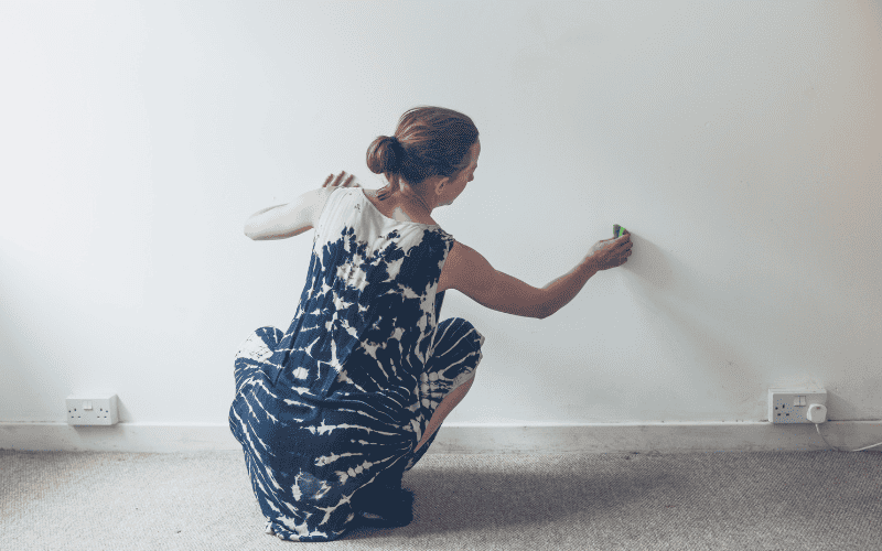 Woman cleaning wall inside of a home.