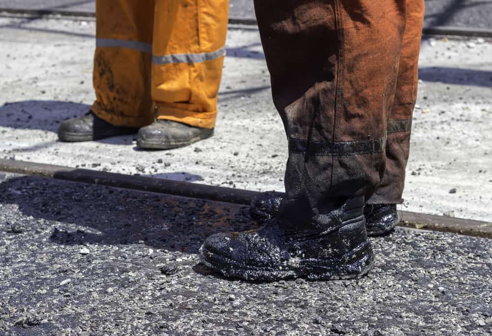 Worker pants and boots stained with tar.